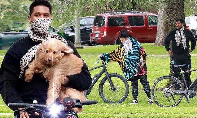 Usher carries his dog as he rides bicycle on outing with girlfriend in LA amid coronavirus lockdown - dailymail.co.uk