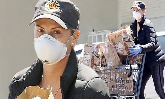 Charlize Theron - Charlize Theron covers up in a mask and a down jacket as she waits in line at the grocery store - dailymail.co.uk - city Beverly Hills