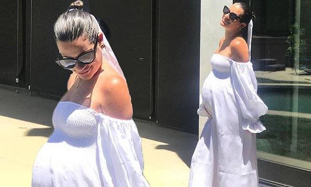Pregnant Lea Michele cradles her baby bump wearing a white flowing dress - dailymail.co.uk