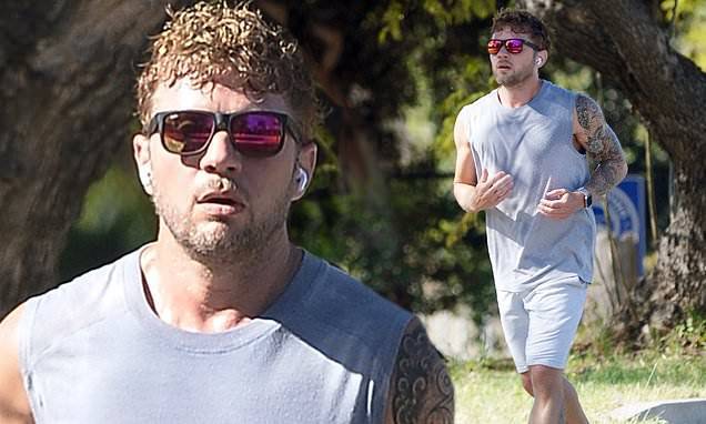 Ryan Phillippe - Ryan Phillippe shows off bulging biceps and tattoos as he jogs in LA in gray tank top and shorts - dailymail.co.uk - Los Angeles